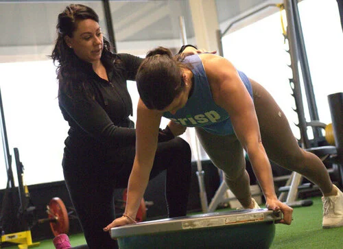 Bree helping keep a woman's form as they perform a plank